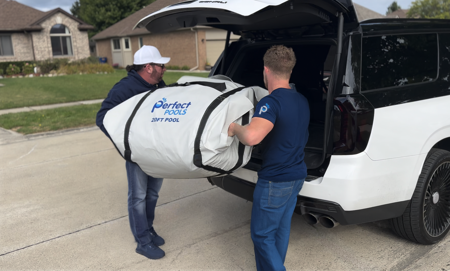 Two men loading a rolled‑up Perfect Pool into the back of an SUV, illustrating portability and easy storage compared to traditional pools